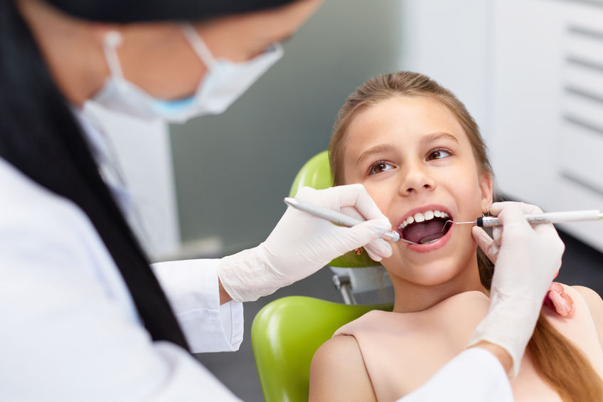 Teeth checkup at dentist's office. Dentist examining girls teeth